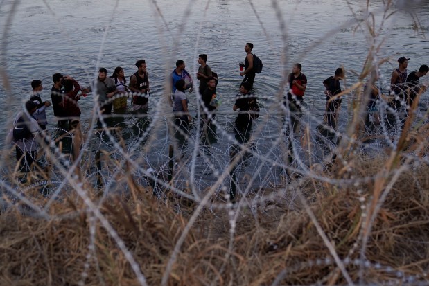 FILE - Migrants wait to climb over concertina wire after they crossed the Rio Grande and entered the U.S. from Mexico, Sept. 23, 2023, in Eagle Pass, Texas. (AP Photo/Eric Gay, File)
