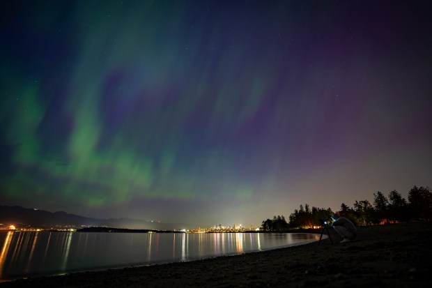 A person takes a photo of Aurora Borealis or the Northern Lights in Vancouver, B.C., Saturday, May. 11, 2024. Brilliant purple, green, yellow and pink hues of the Northern Lights were reported worldwide, with sightings in Germany, Switzerland, London, and the United States and Canada.